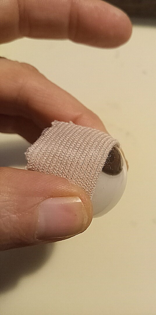 Fold bandage around eye and hold while using hot glue