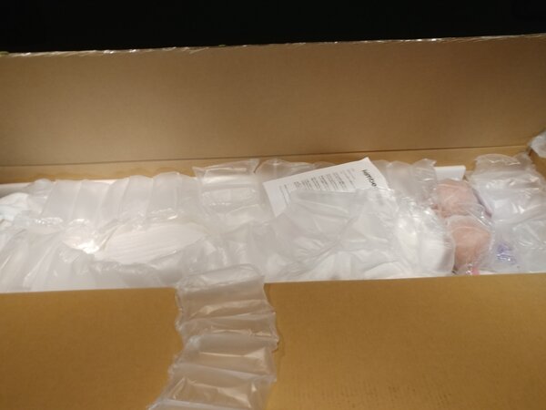 Box flaps opened. (Breasts visible on the right.)